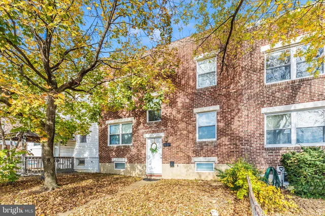 front view of a brick house with a large trees