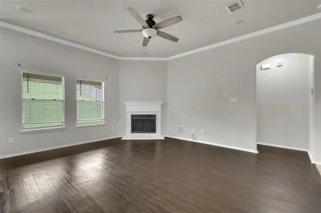 a view of an empty room with wooden floor fireplace and a window