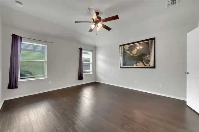 an empty room with wooden floor and a ceiling fan