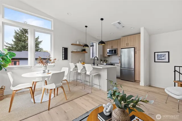 a kitchen with stainless steel appliances a dining table chairs a sink and dishwasher a refrigerator with wooden floor