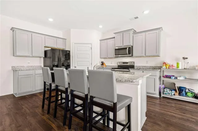 a kitchen with a dining table chairs refrigerator and microwave
