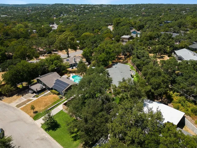 an aerial view of residential house with outdoor space and trees all around