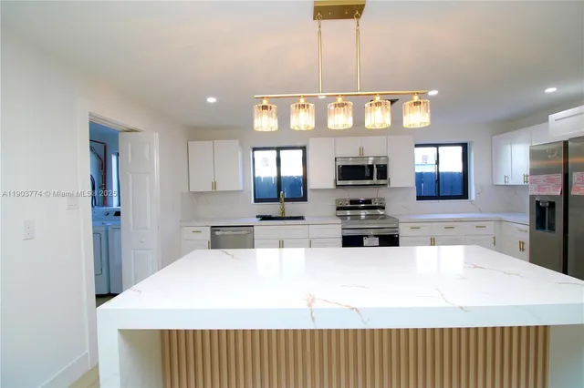 a large kitchen with stainless steel appliances kitchen island a large counter top and a wooden floor