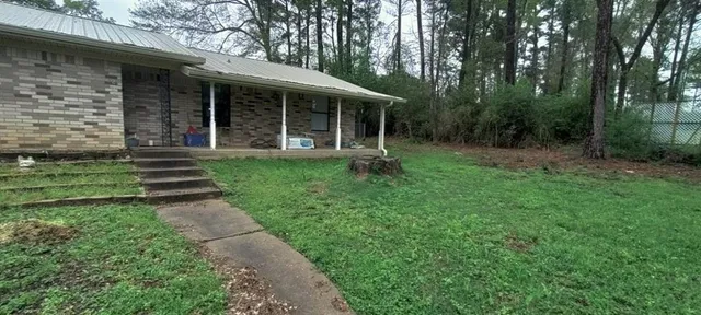 a view of a brick house with a big yard and large trees