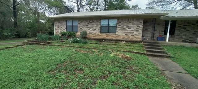 a view of a white house with a big yard and large trees