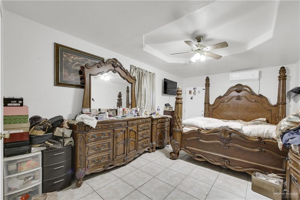 309 Domingo Navarez Street Rio Grande City, TX 78582 - Photo 12 of 14 Bedroom featuring light tile patterned floors, a ceiling fan, and a tray ceiling