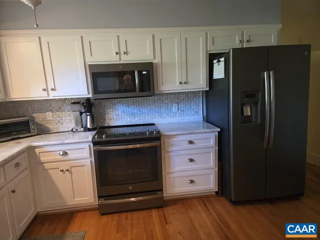 a kitchen with granite countertop white cabinets and stainless steel appliances