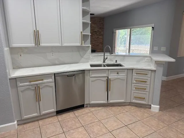 a kitchen with white cabinets stainless steel appliances a sink and a window