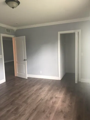 a view of an empty room with wooden floor and closet