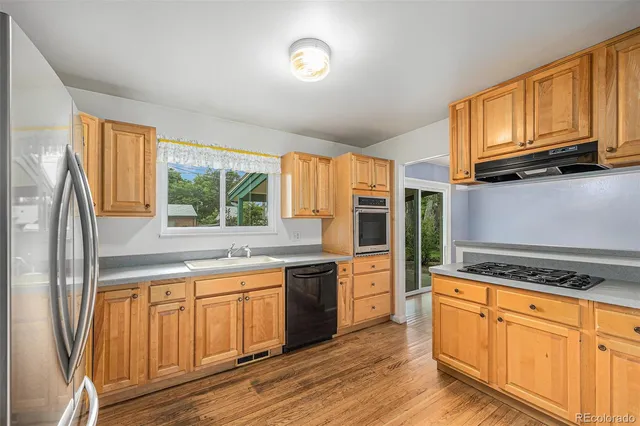a kitchen with granite countertop a refrigerator stove top oven and sink