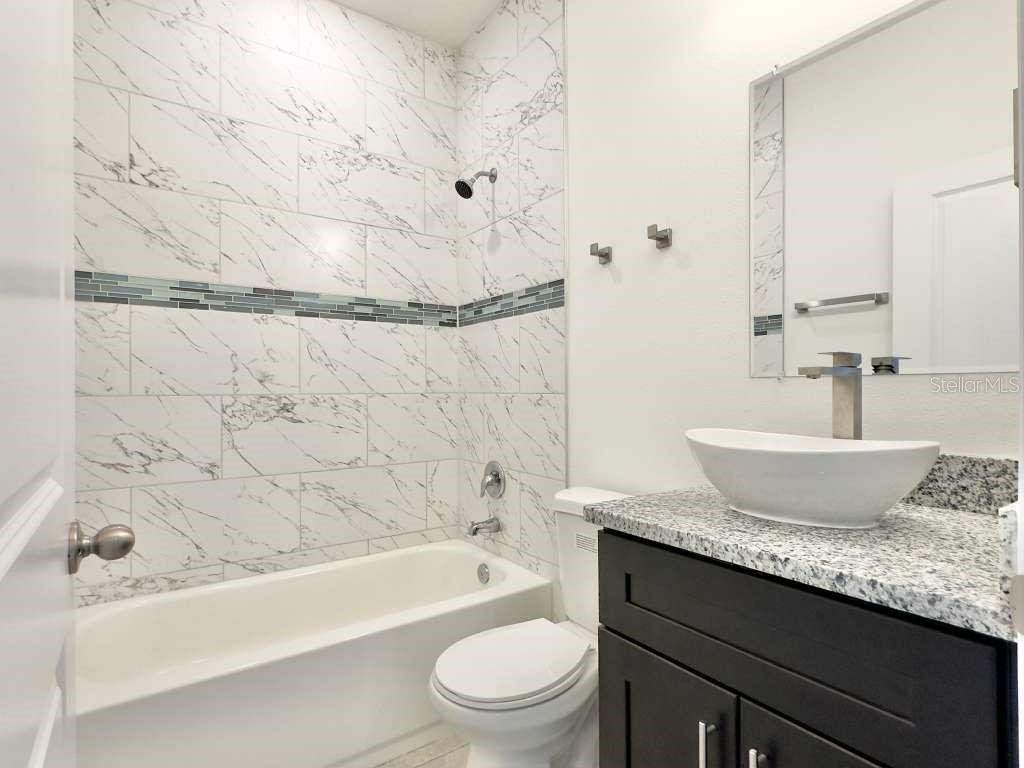 15885 Southwest 35th Court Road, Unit 1 Ocala, FL 34473 - Photo 17 of 27 a bathroom with a granite countertop sink a toilet and bathtub