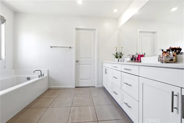 a spacious bathroom with a tub sink and mirror