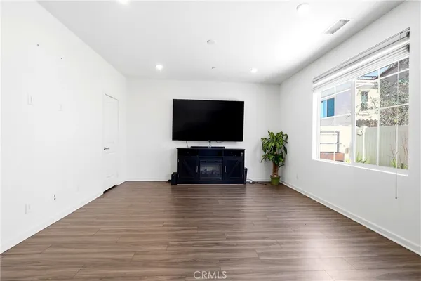 a view of an empty room with wooden floor and a flat screen tv