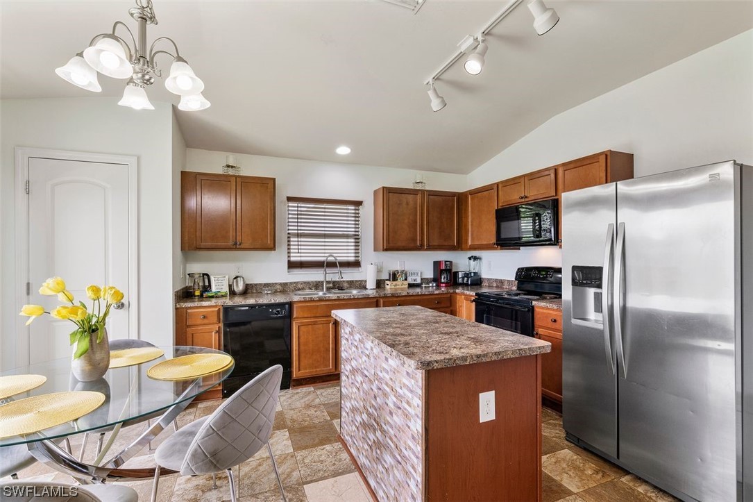 18520 Sebring Road Fort Myers, FL 33967 - Photo 10 of 24 a kitchen with granite countertop stainless steel appliances a sink dishwasher a refrigerator a stove top oven a dining table and chairs with wooden floor
