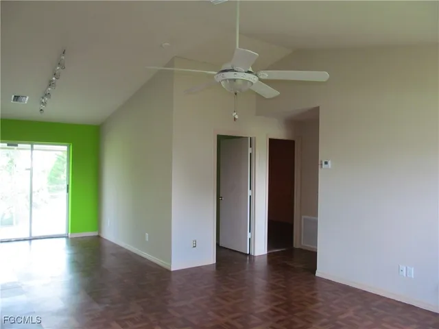 a view of an empty room with a window and wooden floor