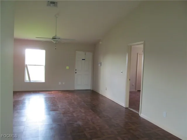 an empty room with wooden floor closet and windows