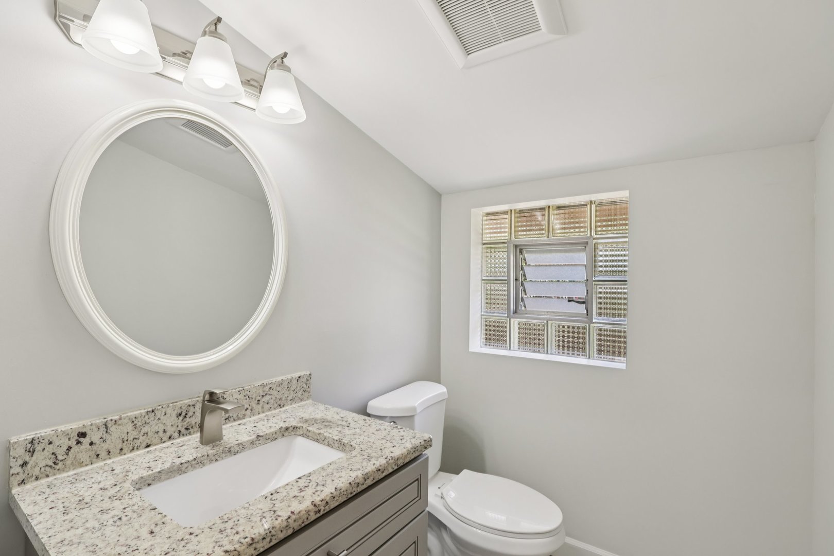 195 7th Street Wheeling, IL 60090 - Photo 25 of 34 a bathroom with a granite countertop toilet a sink and a mirror