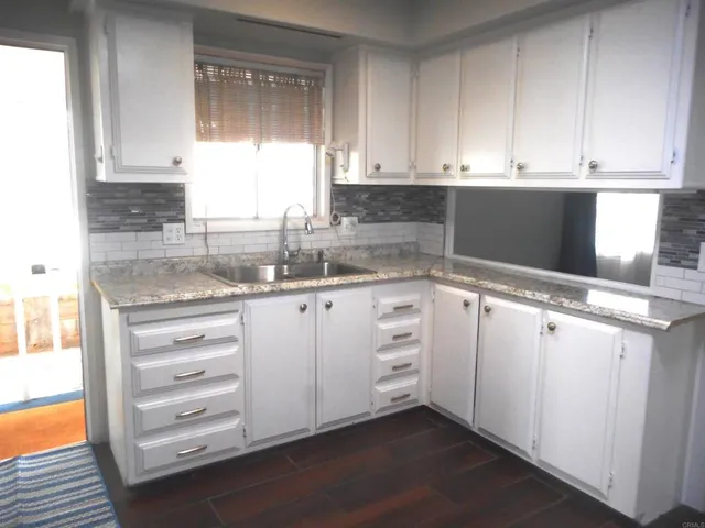 a kitchen with granite countertop white cabinets and white appliances