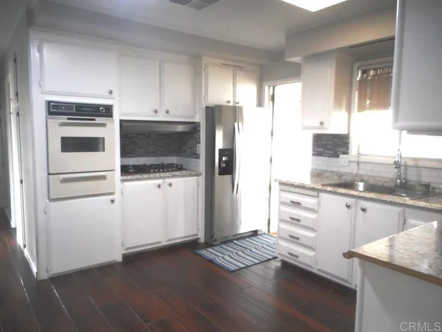 a kitchen with granite countertop a refrigerator stove and sink