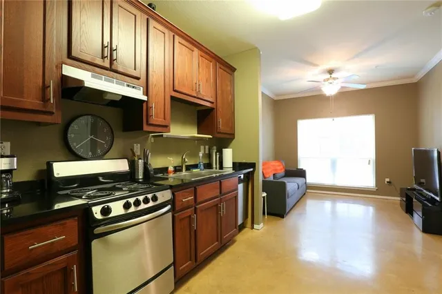 a kitchen with stainless steel appliances granite countertop a stove a sink dishwasher and cabinets with wooden floor