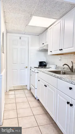 a kitchen with granite countertop white cabinets and white appliances