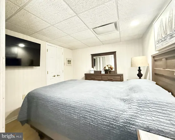 a bedroom with a bed a mirror and a flat tv screen on dresser