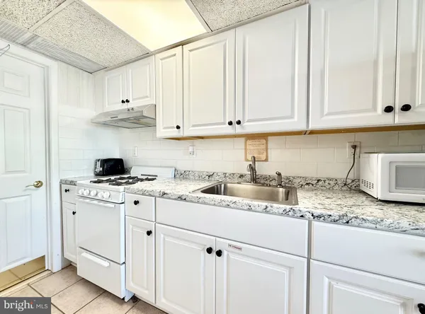 a kitchen with granite countertop white cabinets and white appliances
