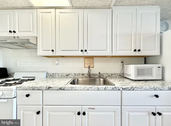 a kitchen with granite countertop white cabinets and sink