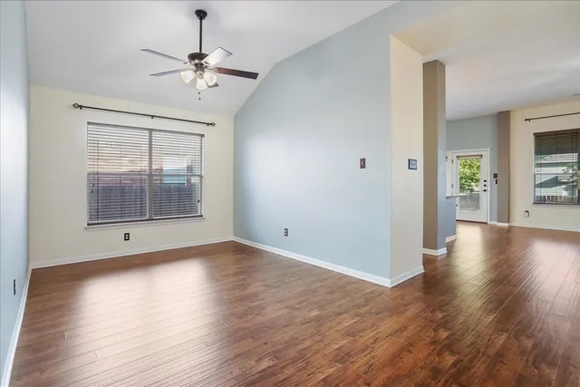 an empty room with wooden floor chandelier and windows