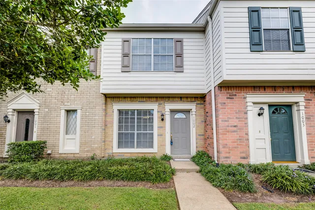 a view of brick house with a large windows and a large tree