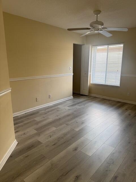 2509 Southeast Springtree Place Stuart, FL 34997 - Photo 18 of 19 an empty room with wooden floor fan and windows
