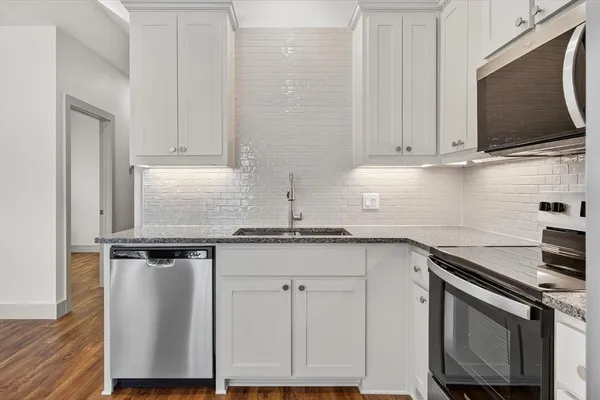 a kitchen with granite countertop white cabinets sink and stainless steel appliances
