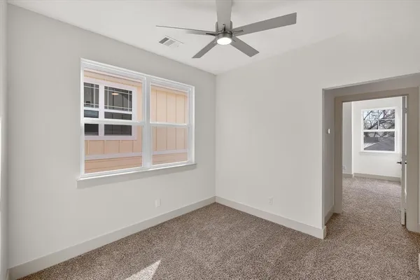 an empty room with a window and a ceiling fan