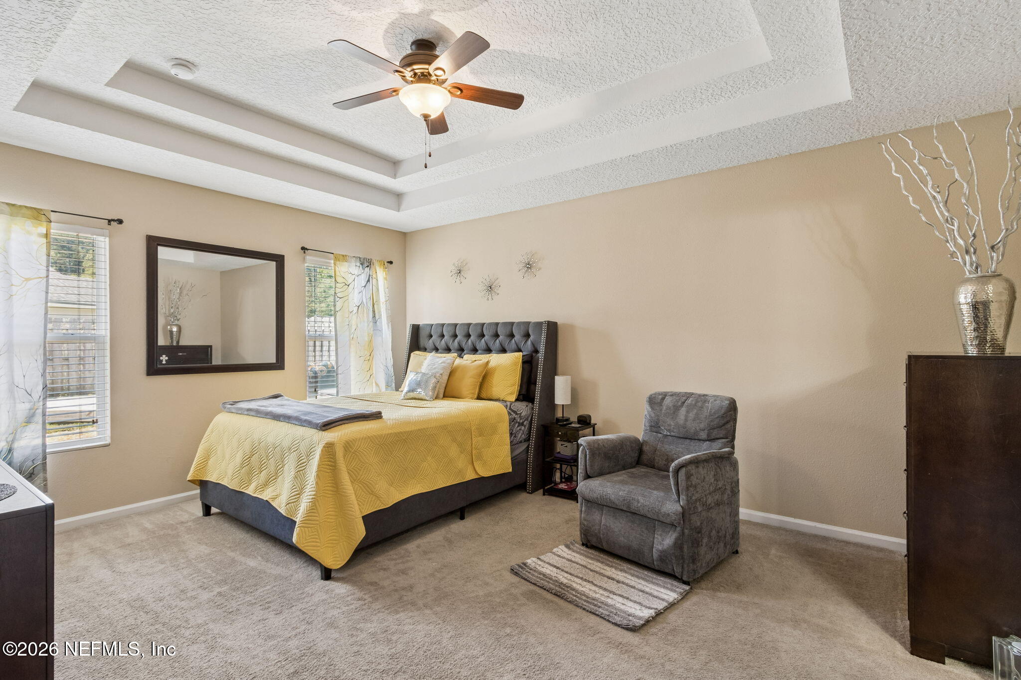 96034 Bass Lane Yulee, FL 32097 - Photo 28 of 50 a spacious bedroom with a bed a couch and a chandelier