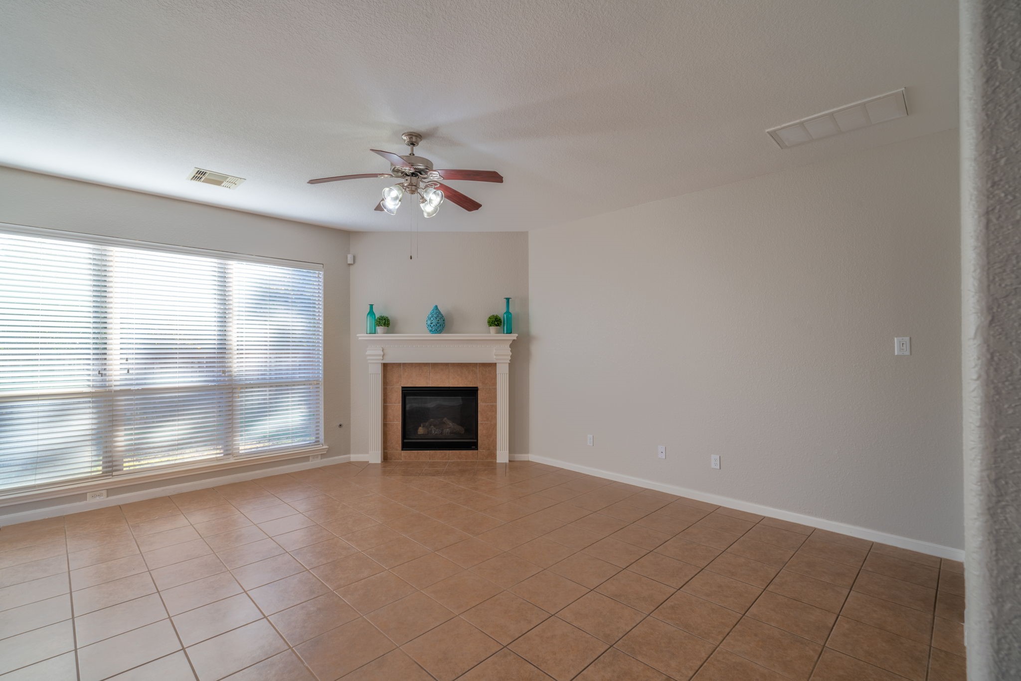 138 Magnolia Grove Lane Conroe, TX 77384 - Photo 15 of 43 a view of an empty room with a fireplace and a chandelier fan