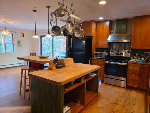 a kitchen with stainless steel appliances granite countertop a sink a stove and a wooden floors