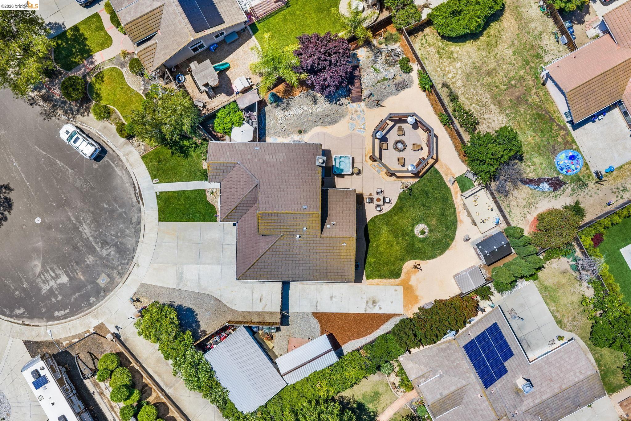 1186 El Rio Court Livermore, CA 94551 - Photo 50 of 60 Expansive property featuring a large concrete driveway, a well-maintained front lawn, and a multi-level rear yard with a distinct octagonal patio area and a separate spa
