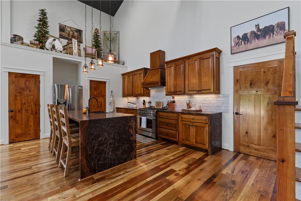 1590 4 Mile Church Road Ball Ground, GA 30107 - Photo 21 of 65 a kitchen with stainless steel appliances kitchen island granite countertop a refrigerator a stove top oven and a sink with wooden floor