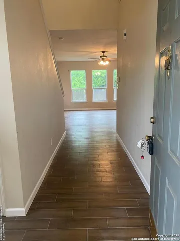 a view of a hallway with wooden floor and a bathroom