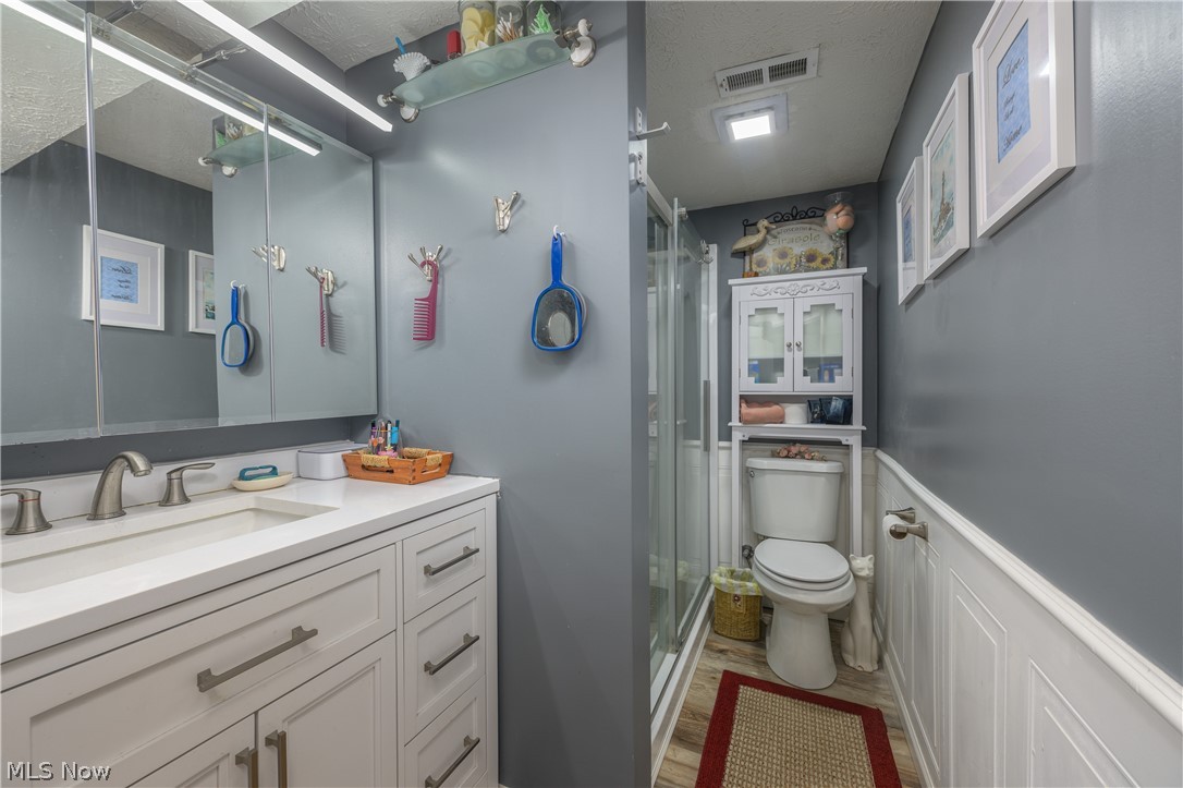 390 Ross Road Waynesburg, OH 44688 - Photo 25 of 30 Bathroom with vanity, a wainscoted wall, a stall shower, a textured ceiling, and light wood-type flooring