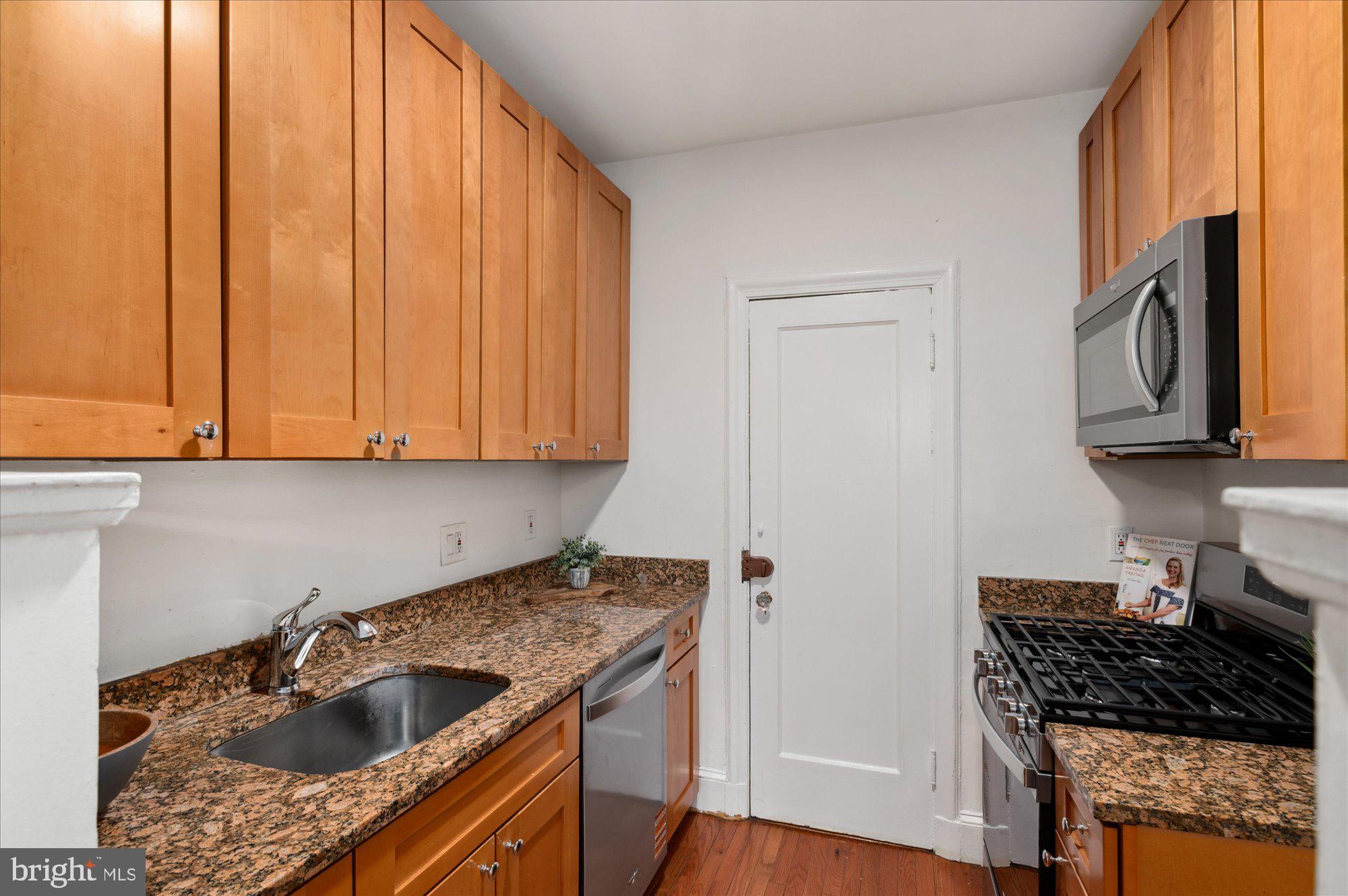 2032 Belmont Road Northwest, Unit 603 Washington, DC 20009 - Photo 10 of 16 a kitchen with granite countertop a sink a stove and cabinets