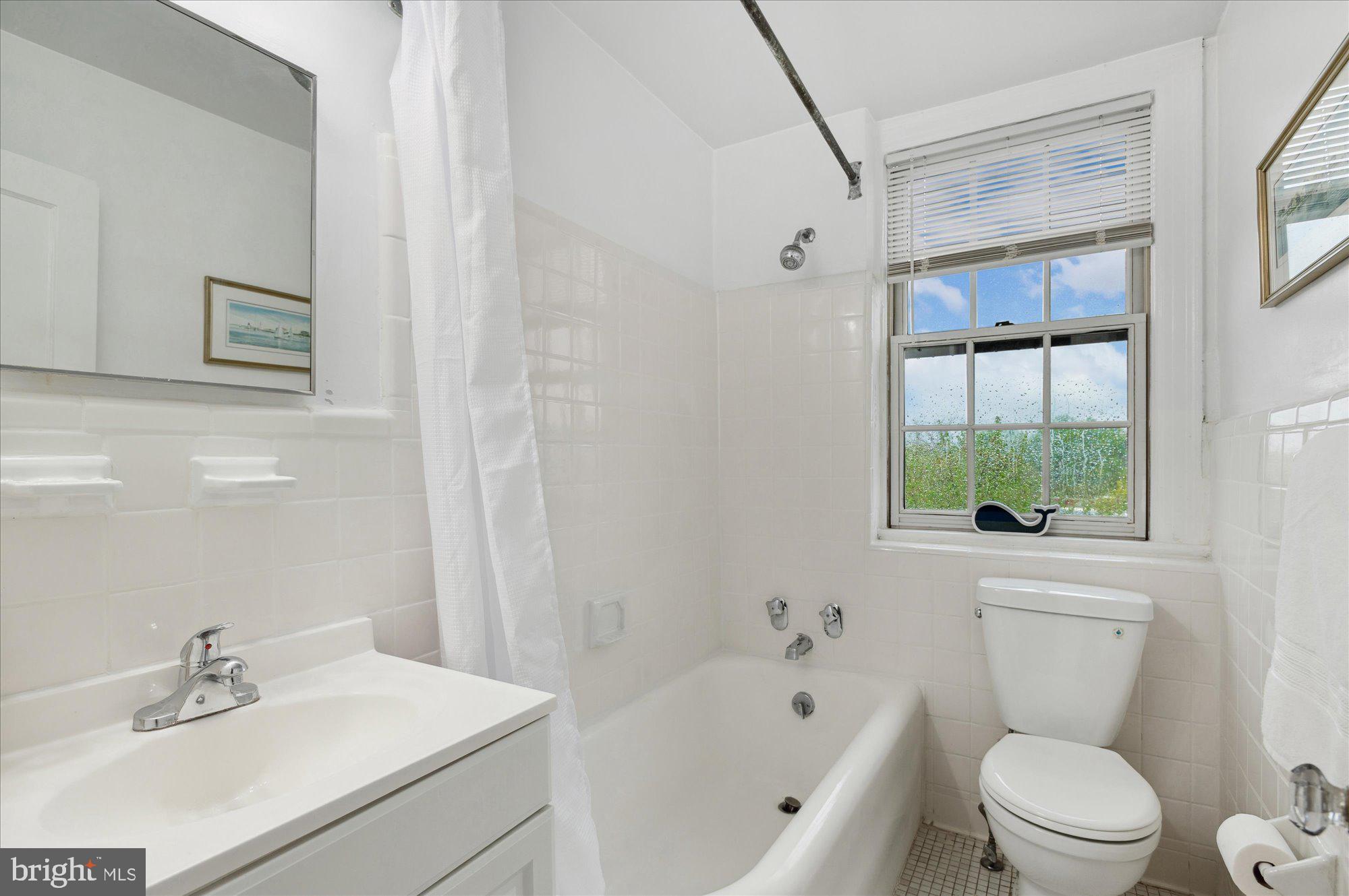 2032 Belmont Road Northwest, Unit 603 Washington, DC 20009 - Photo 13 of 16 a bathroom with a bathtub shower sink vanity and toilet