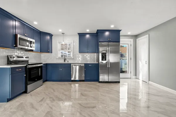 a large kitchen with stainless steel appliances granite countertop a stove a sink dishwasher a refrigerator and a microwave