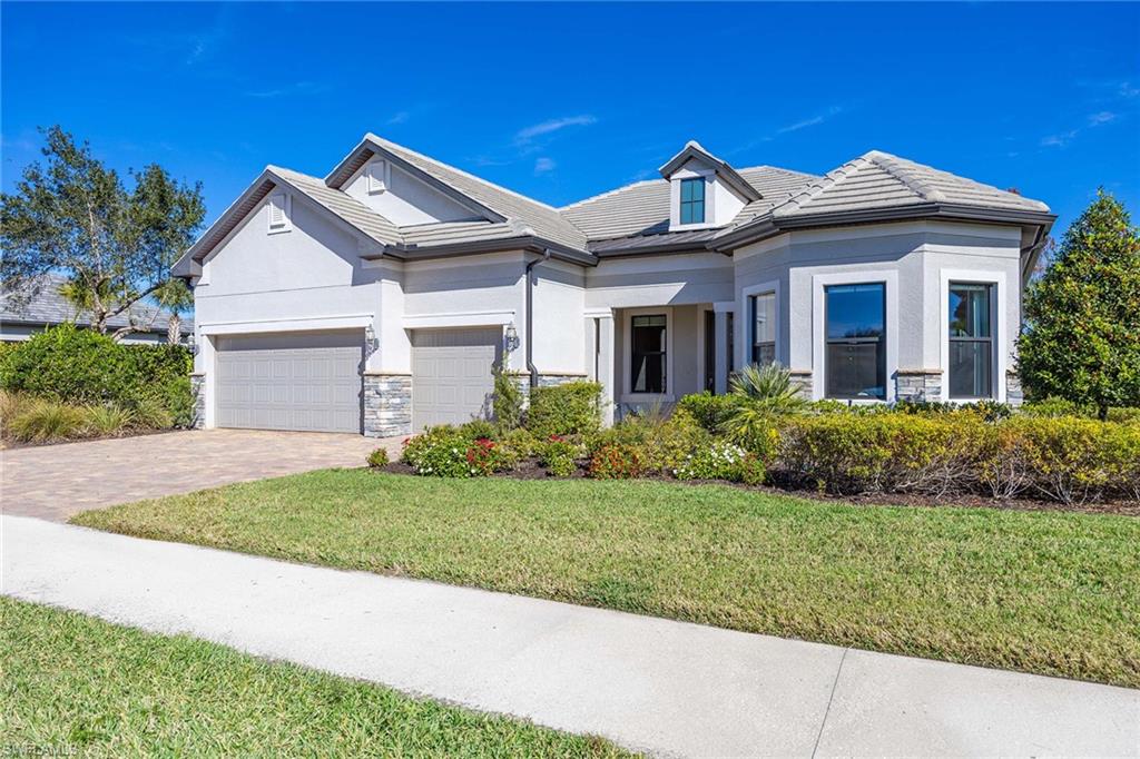 View of front of home featuring a front lawn, driveway, stucco siding, stone siding, and a garage