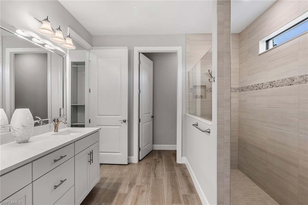 9309 Surfbird Court Naples, FL 34120 - Photo 18 of 45 Bathroom with walk in shower, double vanity, and wood finish floors