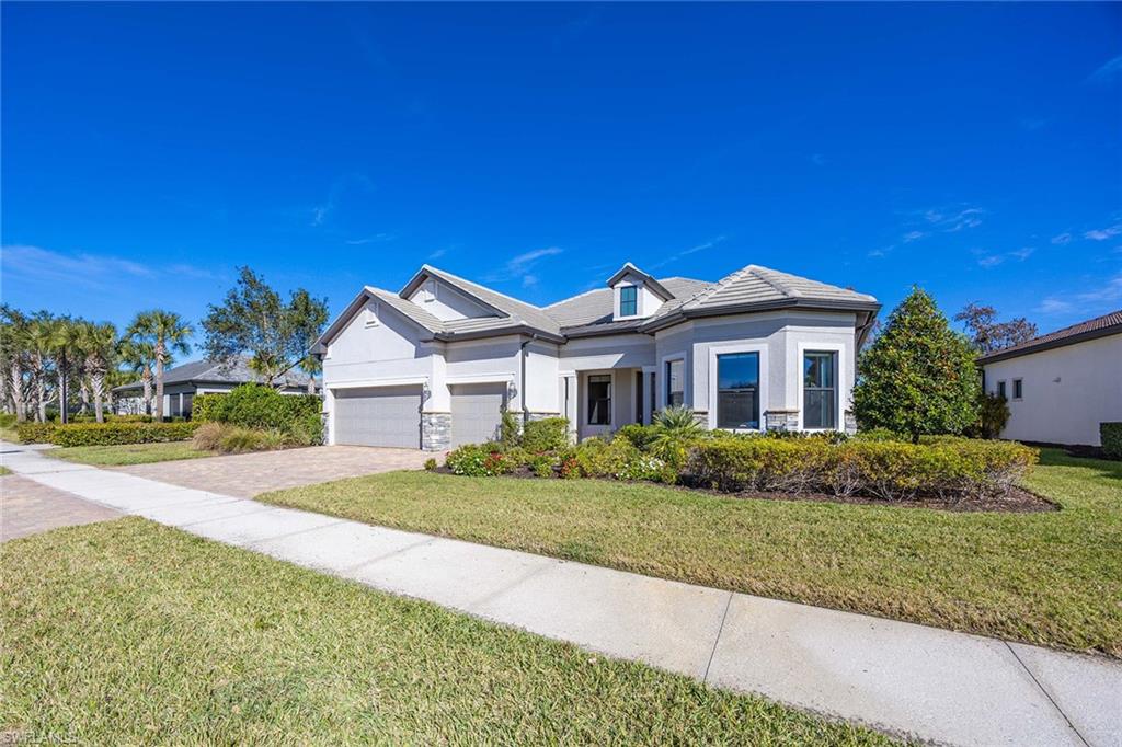 9309 Surfbird Court Naples, FL 34120 - Photo 31 of 45 View of front of home with stucco siding, a front yard, decorative driveway, and stone siding