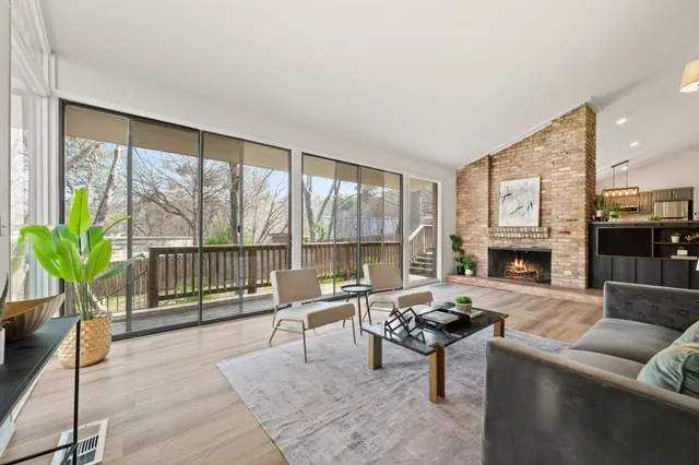 a living room with furniture a floor to ceiling window and potted plants