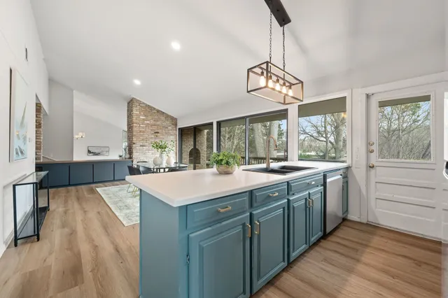 a kitchen with kitchen island granite countertop a sink and wooden floor