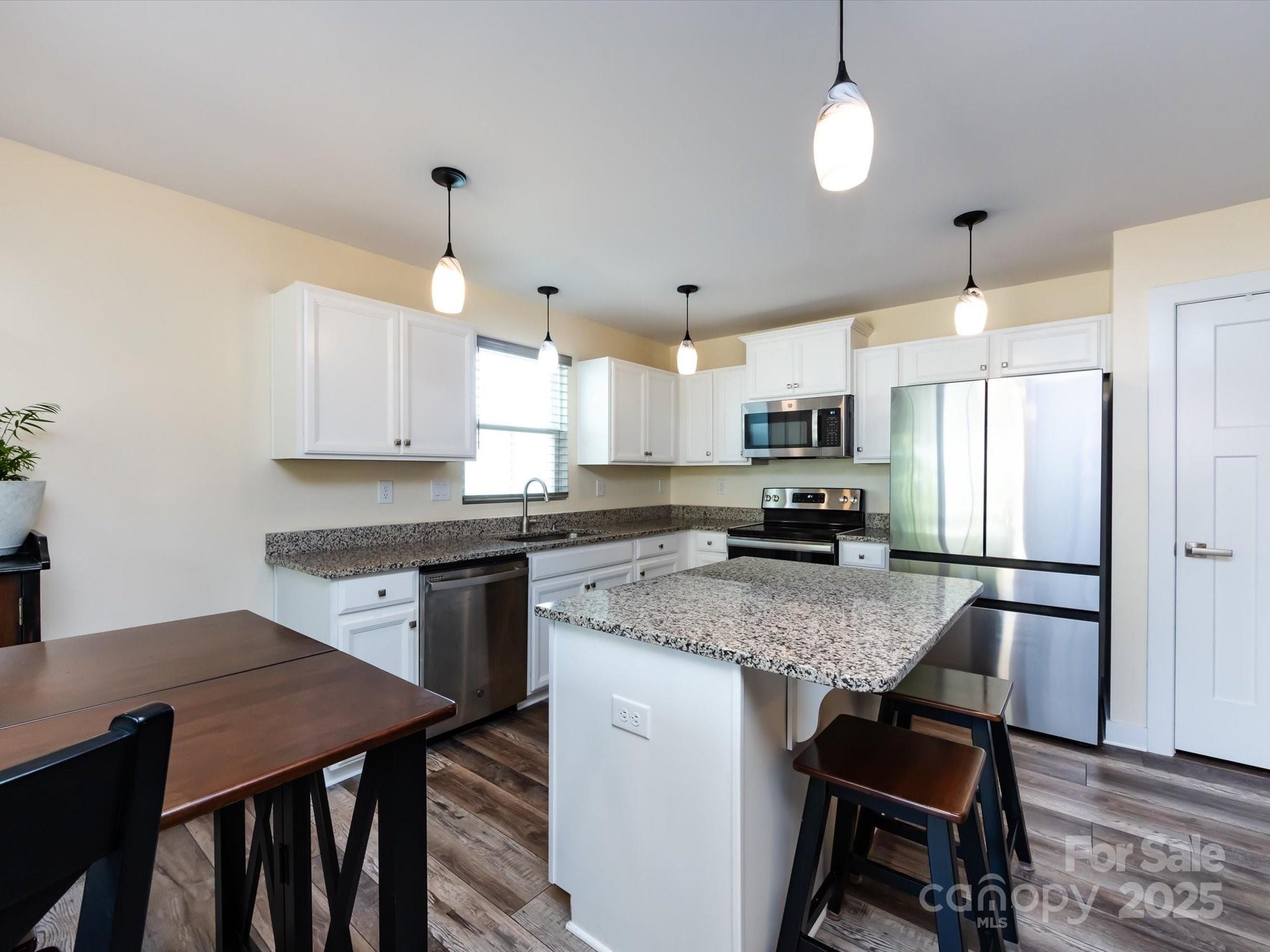 4499 Hunton Dale Road Northwest Concord, NC 28027 - Photo 16 of 43 a kitchen with a stove a refrigerator a sink a dining table and chairs with wooden floor