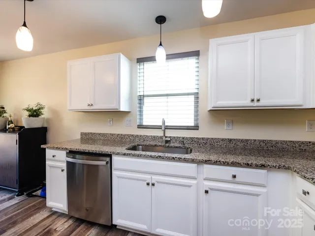 a kitchen with granite countertop white cabinets and a window